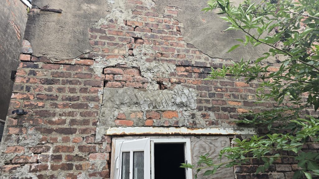 Crumbling brickwork with poor previous repairs on a rear wall
